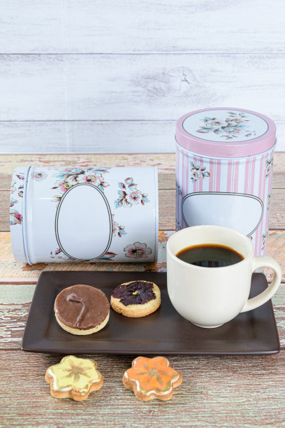 黄油饼干顶部有脱水花，旁边是其他饼干，咖啡杯和罐头(垂直照片)。图片下载