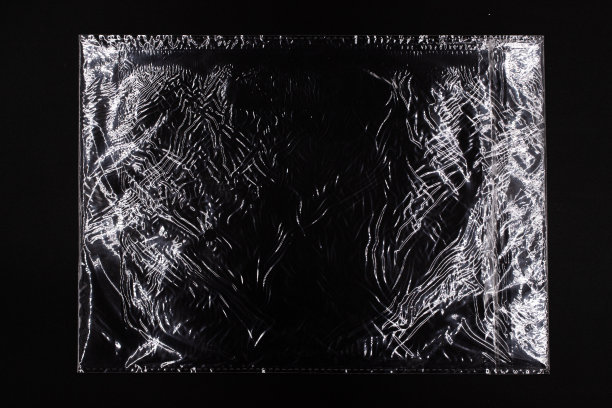 黑色背景上有光泽的塑料袋，塑料文件有刺眼的纹理图片下载