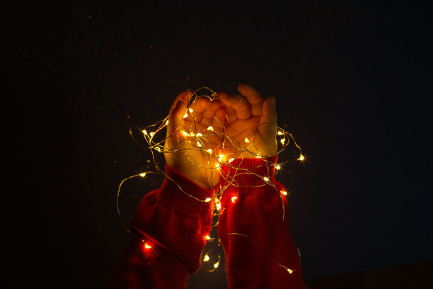 孩子的手牵着五彩缤纷的圣诞装饰灯图片下载