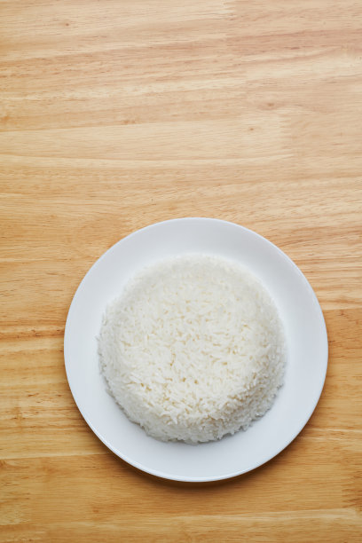 平铺顶视图拍摄的流白泰国的茉莉花米在白色干净的盘子孤立放在木制盘子餐桌靠近一个角落的照片与空白的文本复制空间图片下载