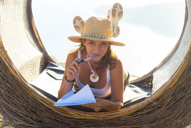 暑假。闻女人放松和阅读在海滩上的书，所以快乐和奢侈的假期夏天，户外蓝天背景。旅游和生活方式概念图片下载