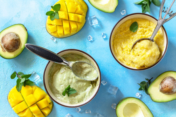 冰淇淋、夏日甜点或甜点。自制牛油果和芒果水果冰淇淋，石头桌上放着热带水果冰沙。俯视图平铺背景。图片下载