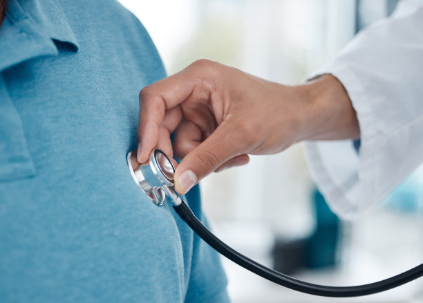 一个不知名的医生在办公室里用听诊器检查一个男人图片下载