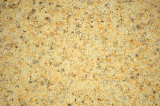 米色花岗岩与小的灰色和黑色夹杂物，抛光的天然石材表面的特写。图片下载
