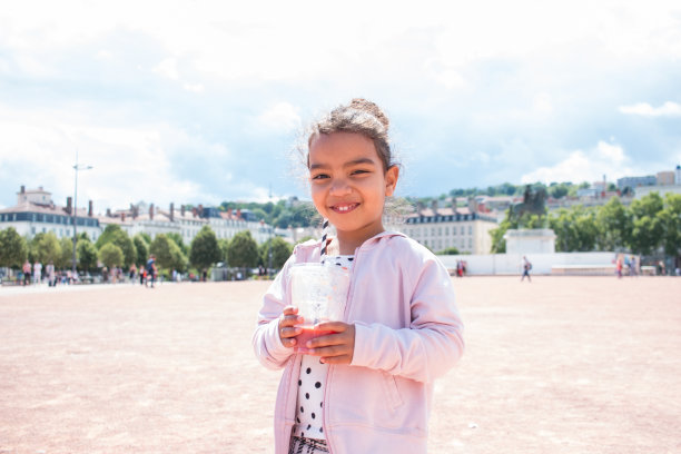 小女孩在城市里喝果汁，享受夏天图片下载