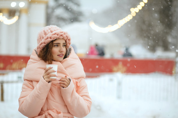 冬季肖像迷人的年轻女士穿着温暖时髦的服装，在基辅圣诞集市喝热茶。空间的文本图片下载