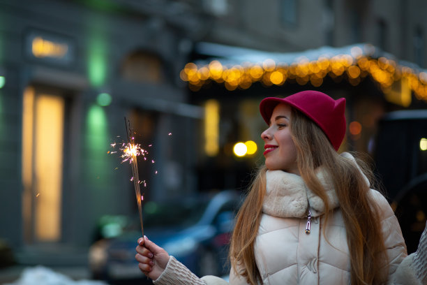 可爱的年轻女士戴着滑稽的帽子和冬装在大街上用烟花庆祝圣诞节。空间的文本图片下载