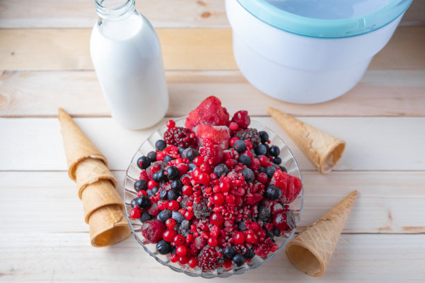 一张木桌的横向照片和上方的照片，上面有自制冰淇淋的原料:红莓、奶油、冰淇淋机和甜筒图片下载