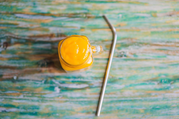 芒果冰沙和钢铁饮用吸管上画的木头背景图片下载