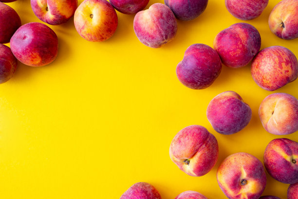 很多成熟的桃子边上衬着黄色的背景，特写图片下载