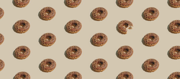 彩色米色背景上的巧克力甜甜圈的创意不规则图案。简约的夏日动感几何排列，甜美可口的食物概念。图片下载