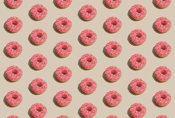 极简主义美学的夏季理念，甜美可口的粉色甜甜圈在柔和的米色背景。创意几何图案排列，美食概念。图片下载