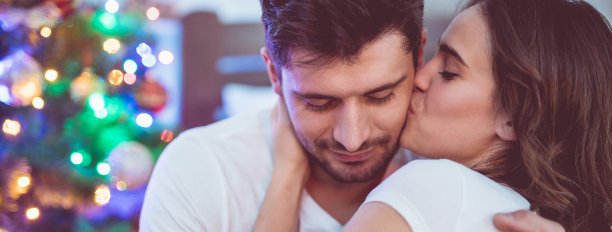 幸福的一对在圣诞树旁接吻图片下载