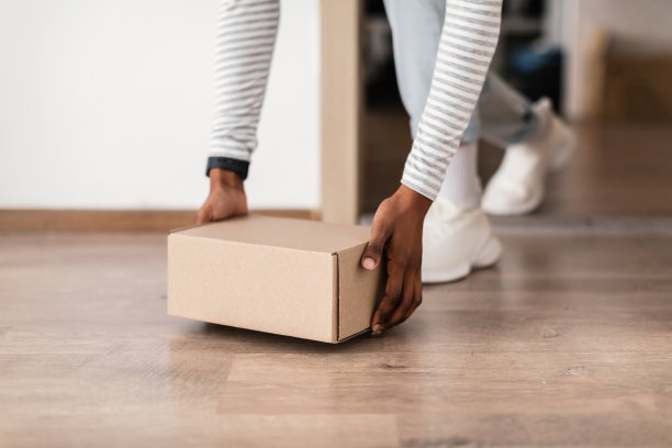 黑人妇女在进门附近拿着纸盒，裁剪图片下载