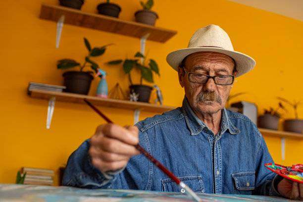 专注的老人，一个艺术家，从他的家庭艺术工作室，画画布，与丙烯颜料图片下载