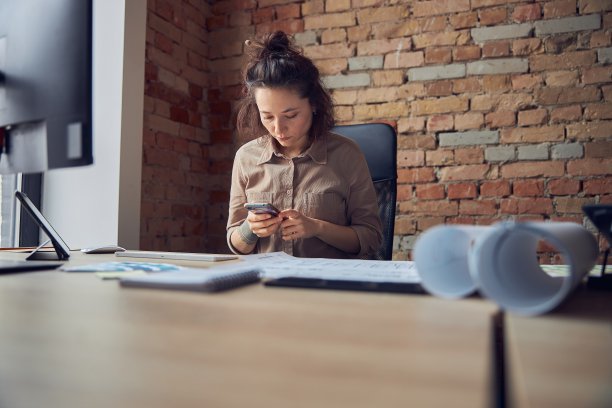 女性室内设计师在办公室工作时使用智能手机图片下载