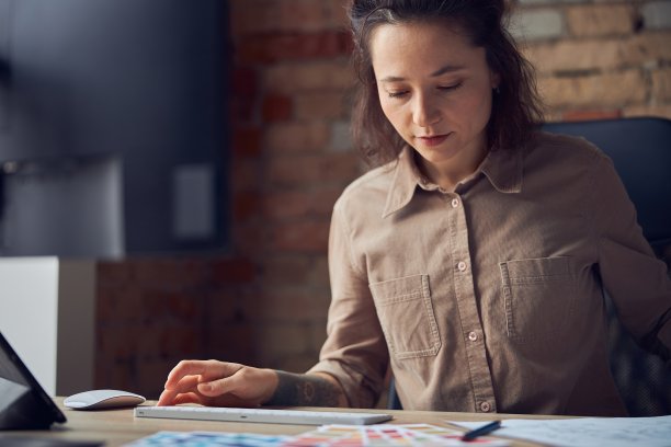 女室内设计师看起来很忙，同时在她的办公室处理图纸，材料样品和电脑图片下载
