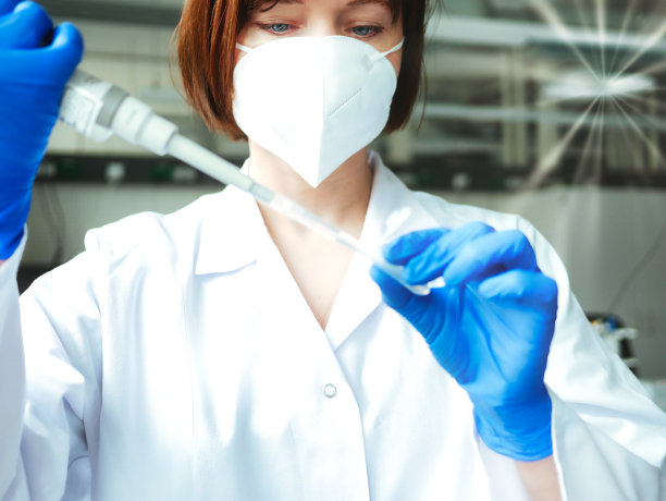 科学家或实验室研究人员戴着防护面罩和实验室手套，手持实验室吸管，将样本移液管入试管。医学诊断、研究和科学背景。图片下载