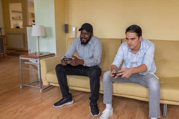 年轻的蓄着胡子的美国黑人和他的朋友在家里用手柄玩电子游戏。图片下载