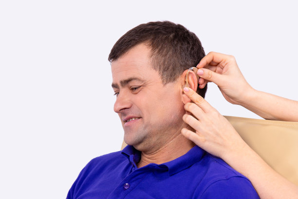 耳鼻喉科医生把助听器放在病人的耳朵里，病人坐在诊疗室里。图片下载