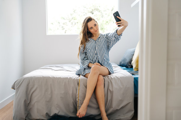 性感女性在家用衣服使用电子设备在她的卧室图片下载
