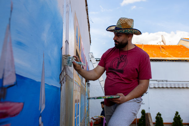 在墙上，专注的男性艺术家画的壁画小威尼斯，同时用他雄伟的笔触创造惊人的艺术品图片下载
