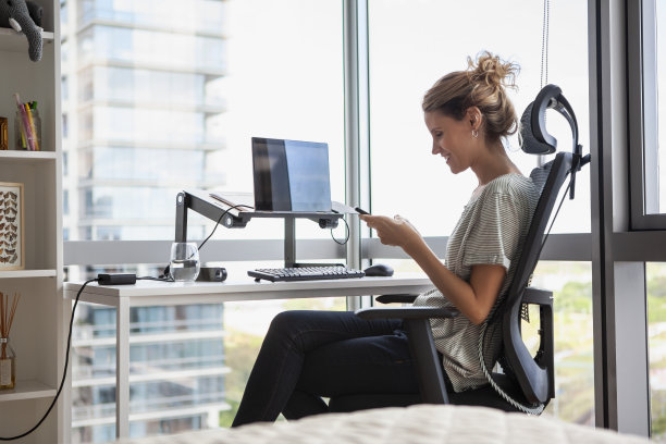 一张中年妇女白天坐在办公椅上使用手机的照片图片下载