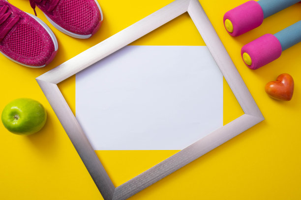 金属框架，白色背景，粉色运动鞋和一个绿苹果，哑铃和一颗心，躺在黄色的背景图片下载