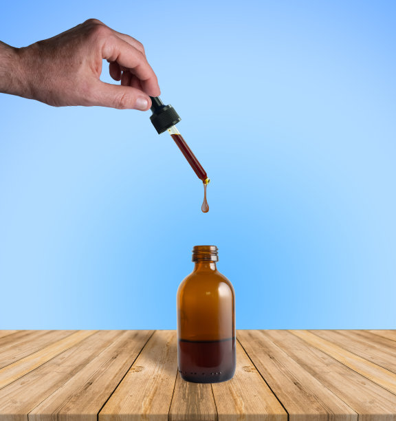 男性的手握着从玻璃滴管上落下的精油。图片下载