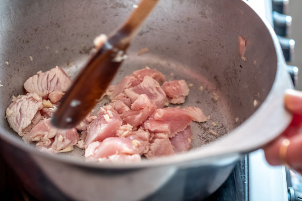 在铁架上的平底锅里翻炒鸡块图片下载