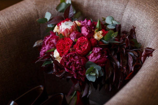 红色婚礼潮流花束的俯视图。新娘花的特写:牡丹，protea，玫瑰和绿色植物图片下载