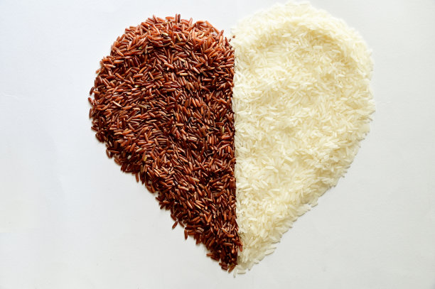 一堆红色的茉莉花米和一颗心形的米孤立在白色的背景上，纵深的田野。图片下载