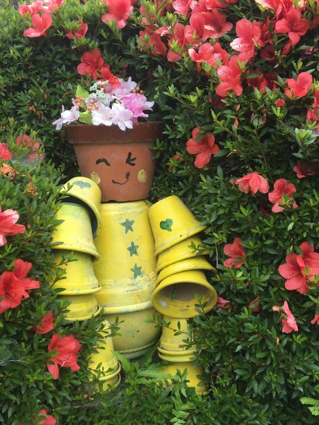 眨眼的花盆雕像被花丛包围图片下载