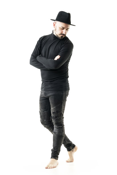 独特风格的年轻人手和黑色高领和牛仔裤赤脚向下看。图片下载