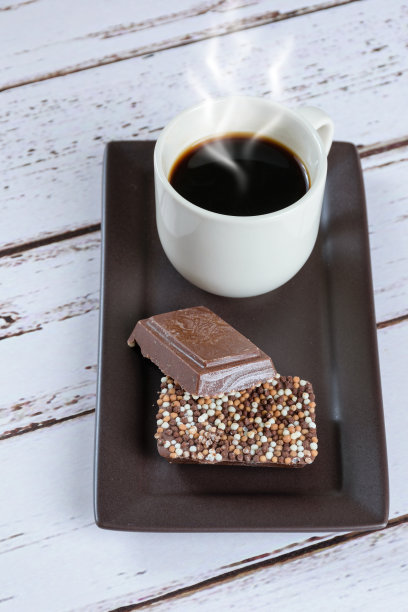 一杯咖啡旁边的牛奶巧克力棒(垂直图片)。图片下载