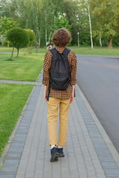 一个人背着背包走在人行道上。垂直的照片。图片下载