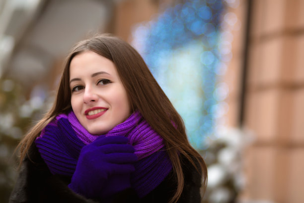 特写的快乐年轻的模特穿着黑色毛皮大衣，摆姿势与蓝色花环的橱窗图片下载