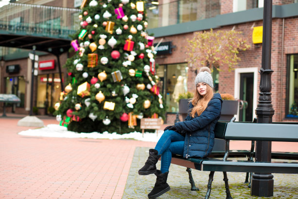 漂亮的红发女人穿着冬天的服装，摆姿势在圣诞云杉的背景图片下载