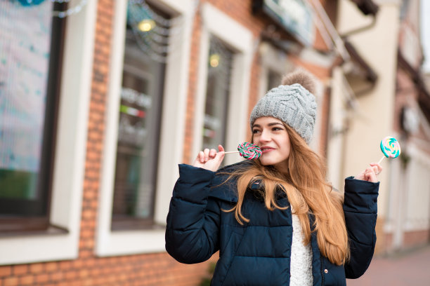 快乐的红发女人戴着灰色针织帽，吃着圣诞糖果图片下载