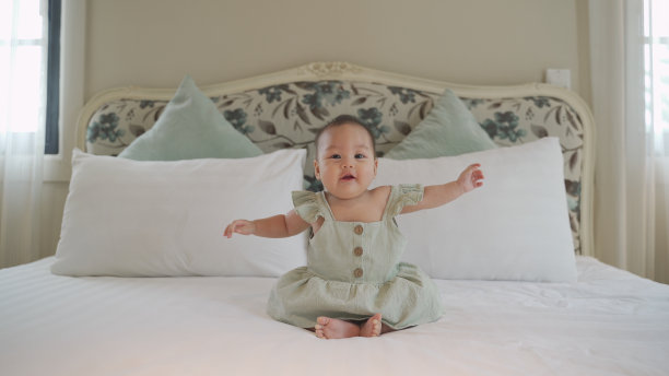 可爱的亚洲婴儿肖像6个月的婴儿学习坐平衡在床上。婴儿看护技能的发展。快乐的微笑宝宝自己在家里玩和高兴。图片下载