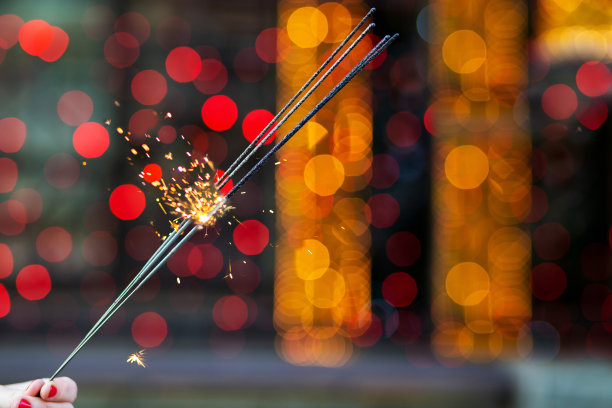 近距离拍摄的女性手拿烟花在花环模糊的背景。空间的文本图片下载