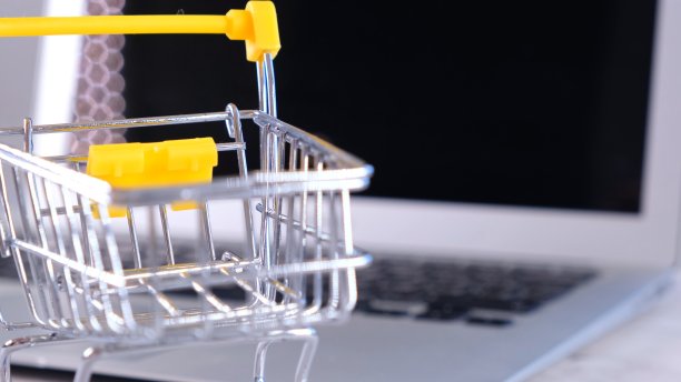 背景是笔记本电脑旁边的购物篮。副本的空间。网上购物的概念图片下载