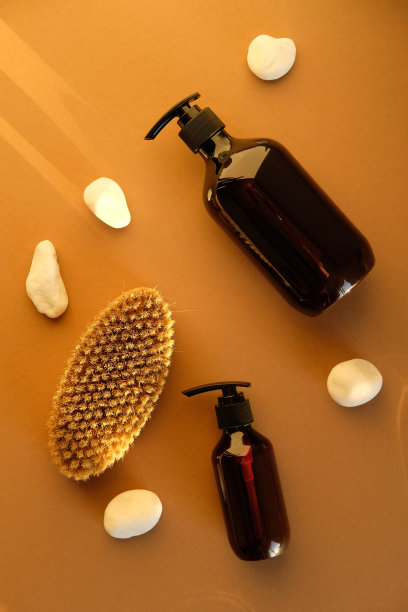 SPA天然有机个人卫生化妆品。装有洗发水和沐浴露的琥珀玻璃瓶，身体刷，棕色背景上的石头。图片下载