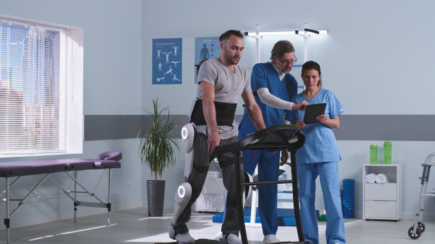 医生在病人的外骨骼附近讨论康复结果图片下载