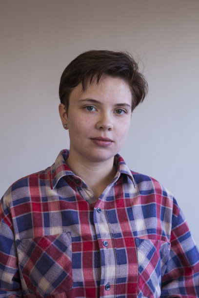 一个年轻女子的肖像没有化妆，穿着随意的格子衬衫。图片下载