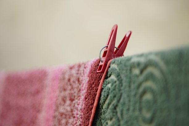 花园里用晾衣夹在绳子上晾干的绿色和紫色毛巾，特写，透视图片下载