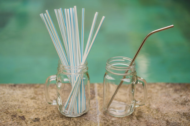 泳池背景上的钢水vs一次性吸管。“零浪费”的概念图片下载