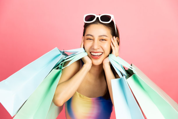 美丽的亚洲女人在比基尼和微笑站在粉红色的背景孤立。暑假快乐的旅行概念。图片下载