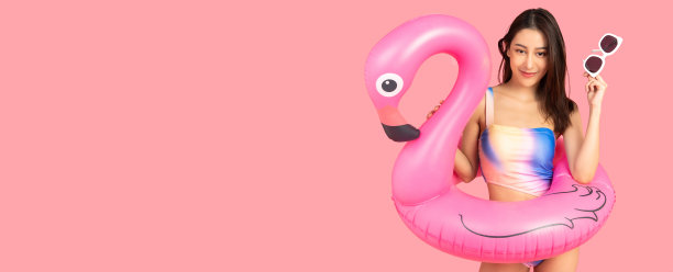 美丽性感的亚洲女人在比基尼和微笑站在粉红色的背景孤立。暑假快乐的旅行概念。图片下载