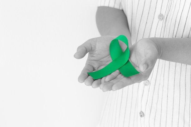 手握翠绿色或翡翠绿色丝带卷在白色背景与复制空间，象征肝癌意识，世界癌症日。医疗保健或医院和保险概念。图片下载